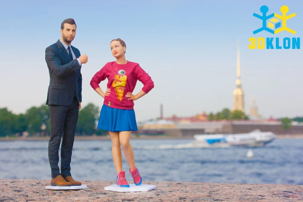 Цветные 3D-фигурки мужчины в костюме и девушки в синей юбке у воды