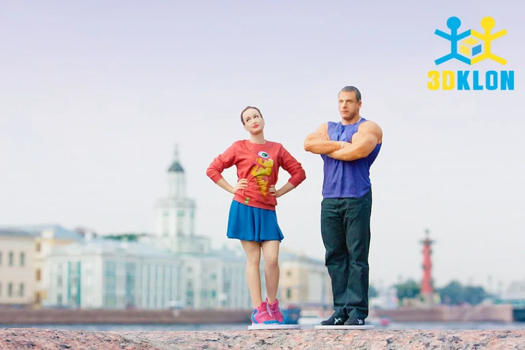 3D-фигурки девушки в синей юбке и мускулистого мужчины на набережной