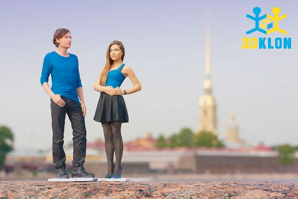 3D-фигурки парня в синей кофте и девушки в короткой юбке на фоне городской набережной