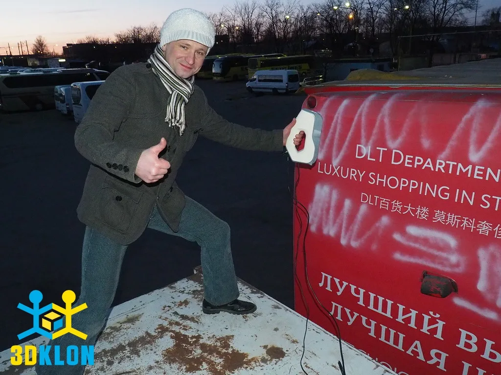 Специалист с ручным 3D-сканером сканирует заднюю часть красного автобуса